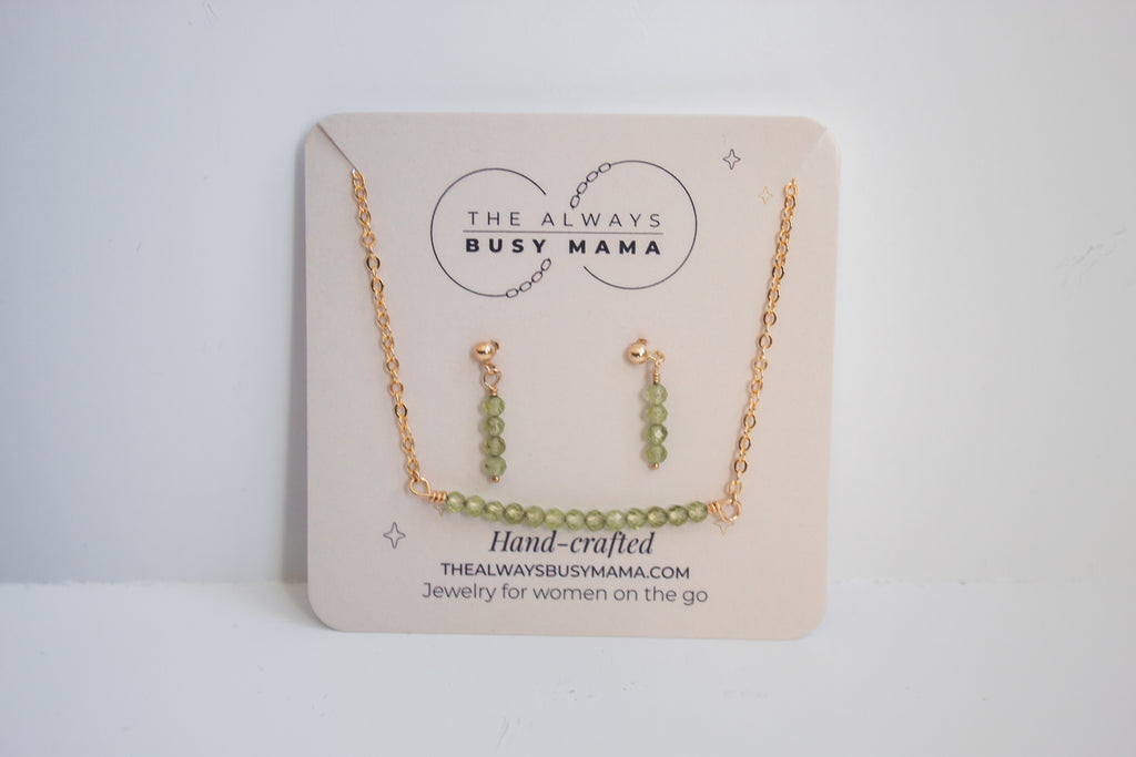 Moments and milestones peridot stud earring and necklace set in 14k gold filled on a jewelry card. 