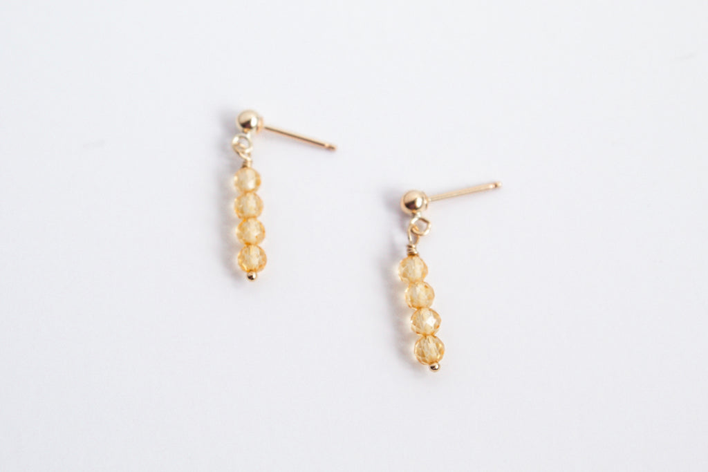 Moment and Milestone stud earrings in 14k gold filled and dangling citrine gemstones, symbolizing life’s meaningful moments, displayed on a white background.