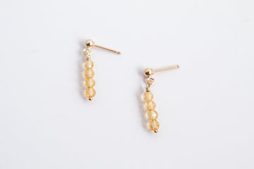 Moment and Milestone stud earrings in 14k gold filled and dangling citrine gemstones, symbolizing life’s meaningful moments, displayed on a white background.