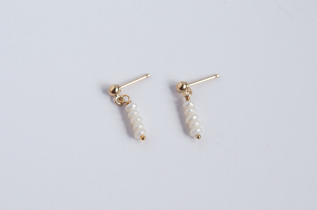 Moment and Milestone stud earrings in 14k gold filled and dangling mini pearl gemstones, symbolizing life’s meaningful moments, displayed on a white background.