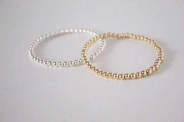 3mm 14k gold-filled and sterling silver metal stretch bracelet, featuring dainty gold and sterling silver beads for a minimalist look, displayed on a white background. 