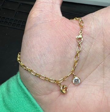 Model holding the Abby chain bracelet in 14k gold filled with april and november cz bezel charm. 