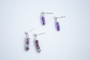 Moment and Milestone stud earrings in sterling silver and dangling amethyst gemstones, symbolizing life’s meaningful moments, displayed on a white background