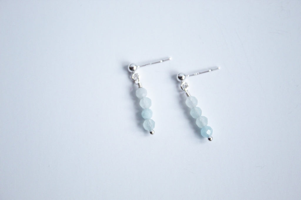 Moment and Milestone stud earrings in sterling silver and dangling aquamarine gemstones, symbolizing life’s meaningful moments, displayed on a white background.