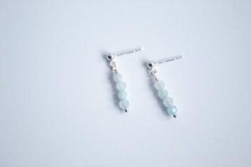 Moment and Milestone stud earrings in sterling silver and dangling aquamarine gemstones, symbolizing life’s meaningful moments, displayed on a white background.