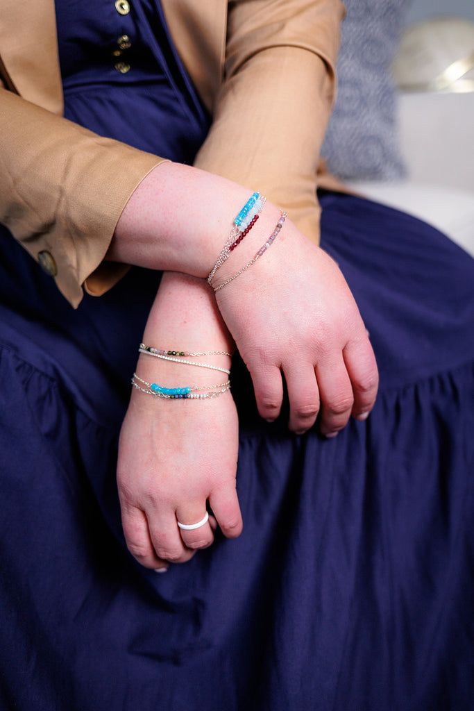 Becky's arms resting with several gemstone bracelets from the moments and milestones collection