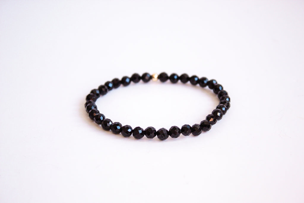 Black onyx gemstone stretch bracelet from the mama's stretch bracelet collection, with one 14k gold filled bead, presented on a pure white background.