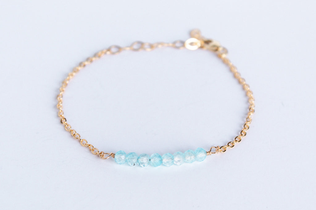 14k gold filled chain bracelet from the Moments and Milestone collection featuring faceted round blue topaz gemstones.