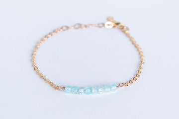 14k gold filled chain bracelet from the Moments and Milestone collection featuring faceted round blue topaz gemstones.