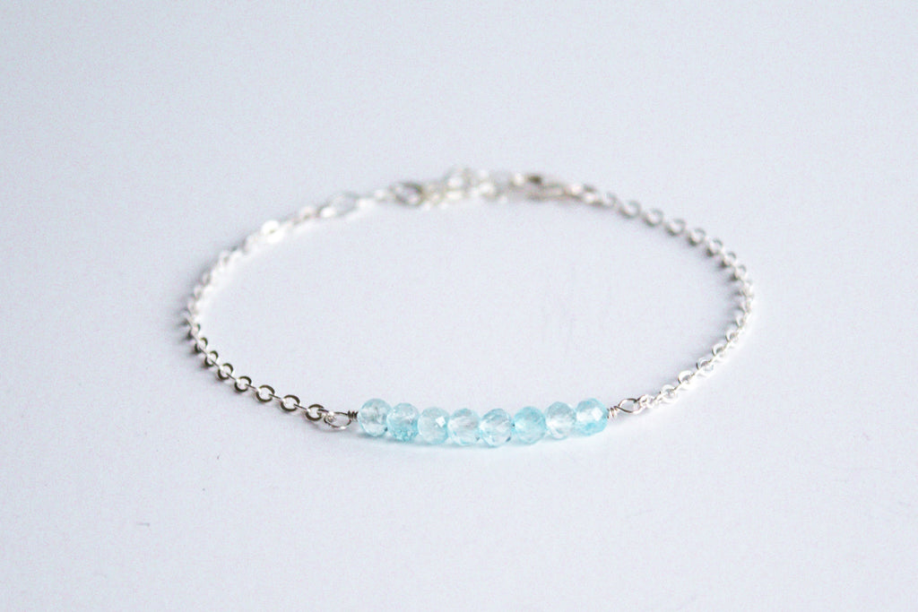 Sterling silver chain bracelet from the Moments and Milestone collection featuring faceted round blue topaz gemstones.