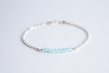 Sterling silver chain bracelet from the Moments and Milestone collection featuring faceted round blue topaz gemstones.