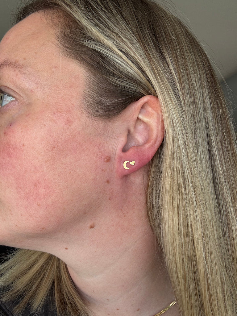 Model wearing crescent and heart studs in 14k gold and 14k gold filled. 