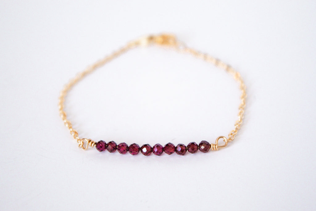 14k gold filled bracelet from the Moments and Milestone collection featuring a faceted garnet gemstones.