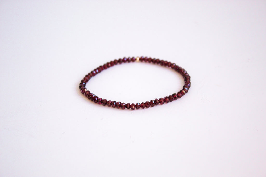 Garnet Rondelle cut gemstone stretch bracelet from the mama's stretch bracelet collection, with one 14k gold filled bead, presented on a pure white background.