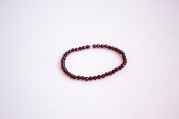 Garnet Round cut gemstone stretch bracelet from the mama's stretch bracelet collection, with one sterling silver bead, presented on a pure white background.