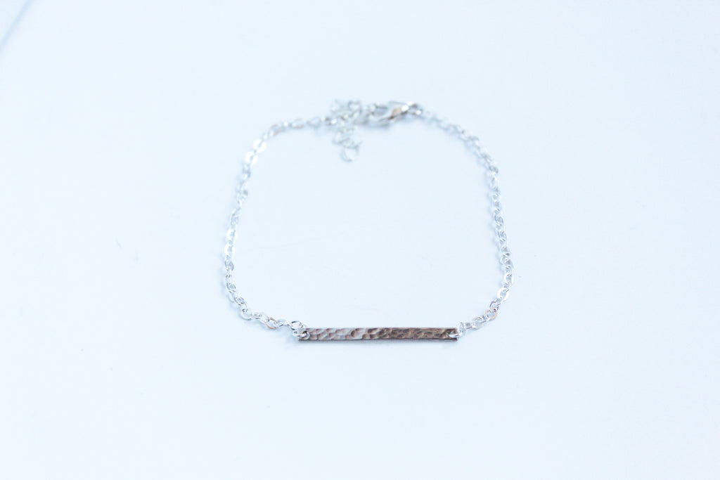 Hammered Bar housed within a sterling silver chain on a white background showcasing the texture of the bar. 