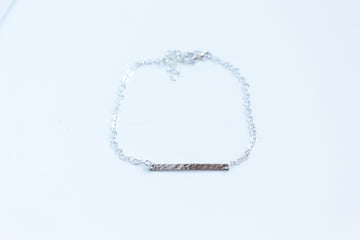 Hammered Bar housed within a sterling silver chain on a white background showcasing the texture of the bar. 