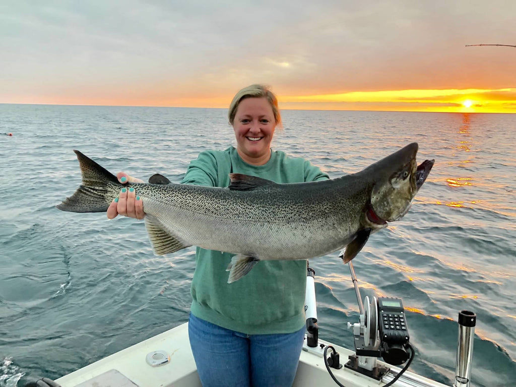 Becky holding a fish at sunset. 