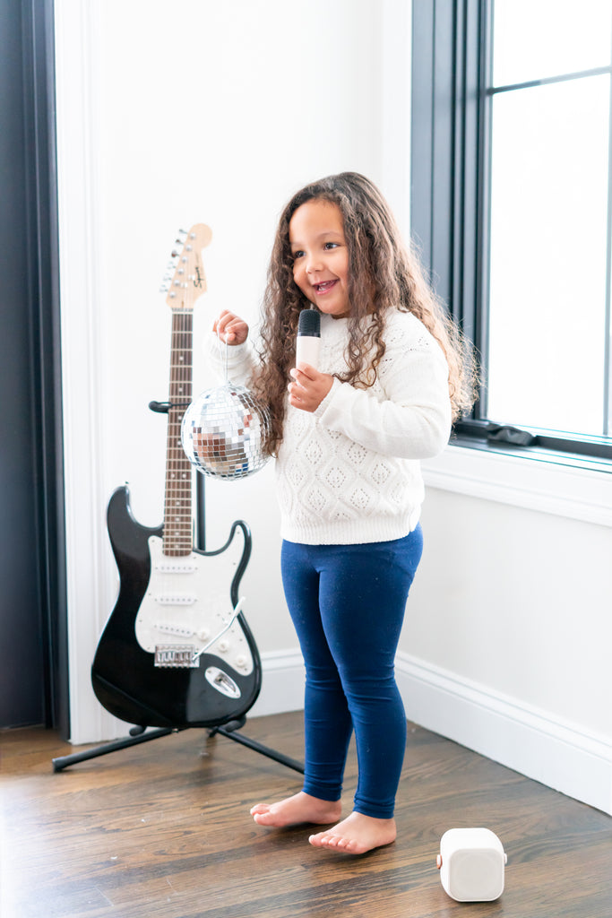 Olivia singing a song with a microphone and a disco ball. 