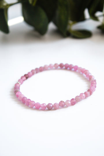 Handcrafted gemstone bracelet with rose quartz beads, styled on a white board for a minimalist display.