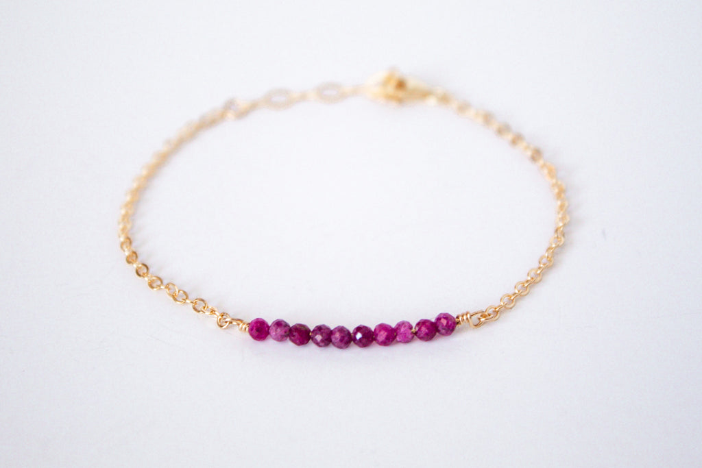 14k gold filled chain bracelet from the Moments and Milestone collection featuring faceted round ruby gemstones.