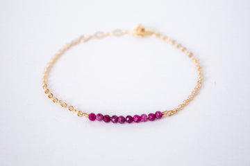 14k gold filled chain bracelet from the Moments and Milestone collection featuring faceted round ruby gemstones.