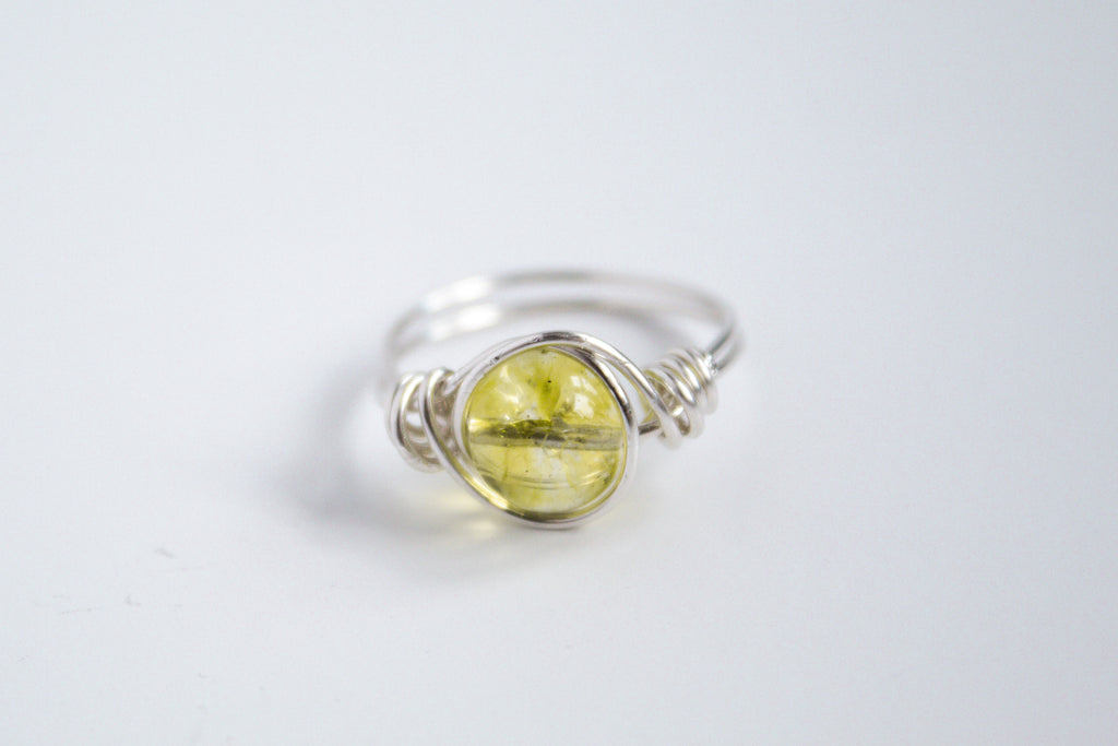 Sterling Silver wire-wrapped ring featuring a peridot gemstone on a white background