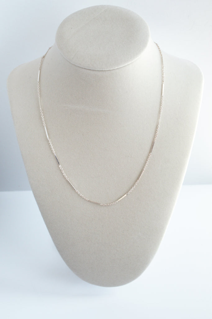 Sterling silver dapped bar necklace, featuring a textured bar pendant, elegantly presented on a necklace display stand.
